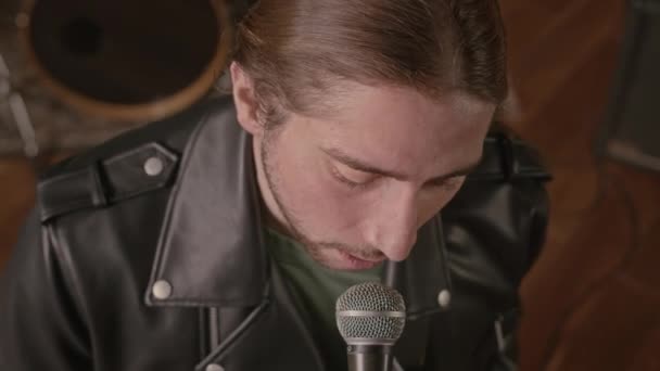 Z výšky POV mladého kavkazského rockového hudebníka zpívajícího v mikrofonu a hrajícího na kytaru ve studiu - Záběry, video