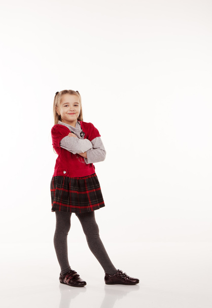 klein meisje in een rode jurk poseren staande in studio - Foto, afbeelding