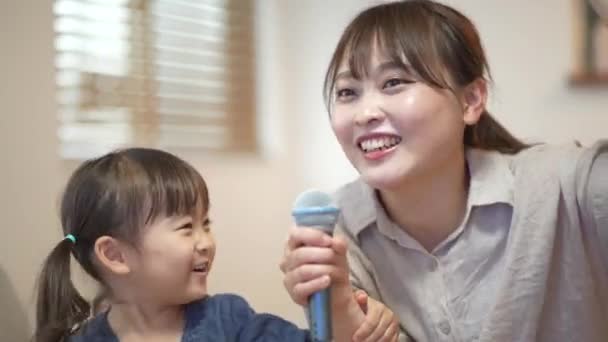 Padres e hijos disfrutando del karaoke en casa - Imágenes, Vídeo