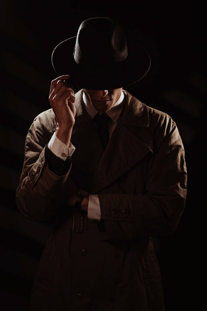 Una silueta oscura de un hombre de la cara con un abrigo y un sombrero. Un retrato dramático al estilo de las películas de detectives y libros de espionaje de las décadas de 1950 y 1960 - Foto, Imagen