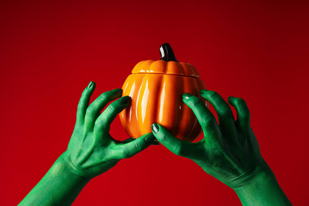 Pumpkin in green hands on red background - Photo, Image