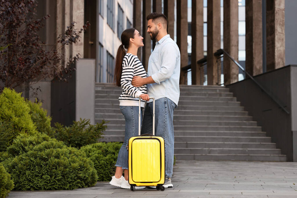 Long-distance relationship. Beautiful young couple with suitcase near building outdoors - Fotografie, Obrázek
