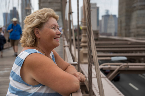 見事なマンハッタンビューでニューヨークを横断する高齢女性 - 写真・画像
