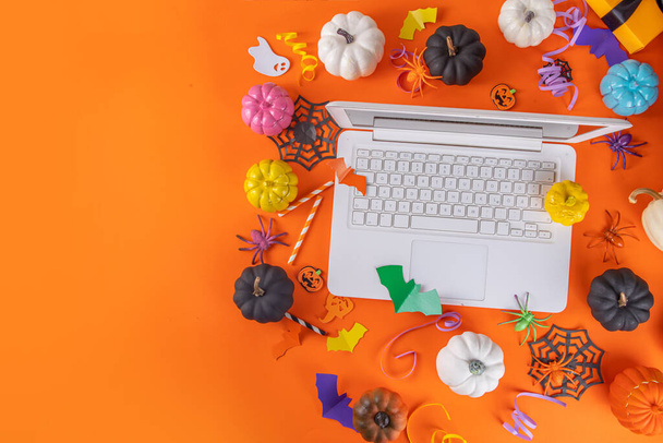Grappige Halloween heldere gele compositie. Witte laptop met typerende skelet handen, Halloween decor kleurrijke vakantie accessoires - spinnen, spinnenwebben, pompoenen, vleermuizen, bovenaanzicht kopieerruimte banner - Foto, afbeelding