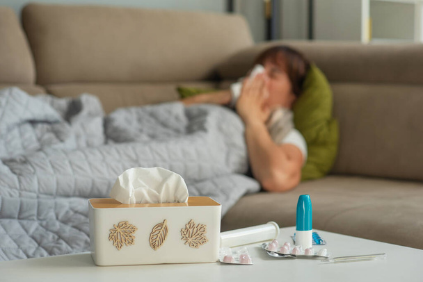病気の中年女性は鼻を吹き飛ばして鼻を保持するティッシュをベッドに座ってくしゃみ,風邪を引いた成熟した女性は自宅だけで薬を服用インフルエンザのグリップ症状を得ました - 写真・画像