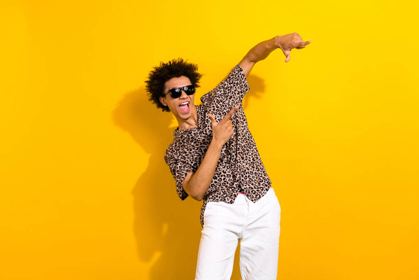 Portrait of crazy eccentric person with chevelure wear leopard shirt sunglass directing at offer isolated on yellow color background. - Foto, afbeelding
