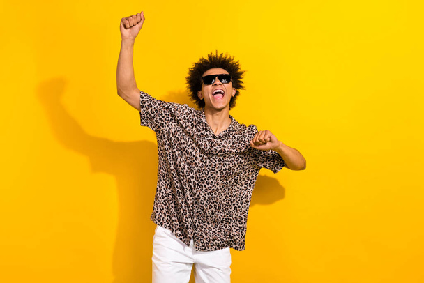 Portret van extatische tevreden persoon met chevelure dragen luipaard shirt zonneglas winnen inzet dansen geïsoleerd op gele kleur achtergrond. - Foto, afbeelding
