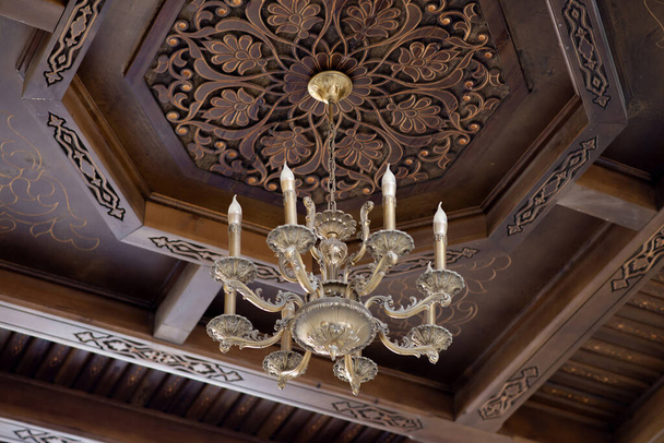 Ancient chandelier on wooden carving ceiling background - Photo, Image