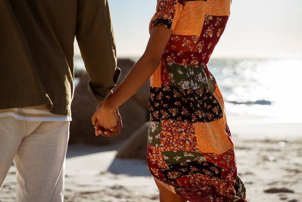 Un couple tenant la main sur la plage au coucher du soleil. Photo de haute qualité - Photo, image