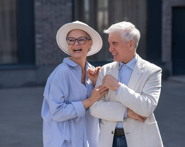 An elderly couple in love walks through the city. Portrait of a stylish gray-haired man and woman - Foto, afbeelding