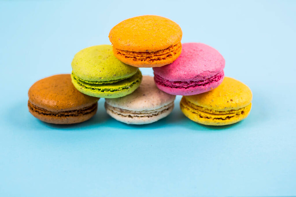 Cake macarons or macaroons on blue background from above, colorful almond cookies, pastel colors - Photo, Image