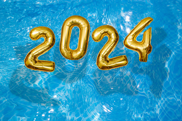 2024 Inflatable golden numbers on water ripples surface, happy new year with a swimming pool concept - Photo, Image