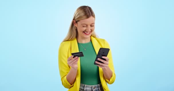 Τηλέφωνο, πιστωτική κάρτα και ευτυχισμένη γυναίκα στο στούντιο με τον προϋπολογισμό, την επένδυση ή την πληρωμή δανείου σε μπλε φόντο. Smartphone, app και ενθουσιασμένοι θηλυκό πελάτη με online ψώνια, εγγραφείτε ή συμφωνία ηλεκτρονικού εμπορίου. - Πλάνα, βίντεο