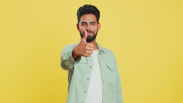 Niin kuin... Intialainen mies nostaa peukalot ylös hyväksyy jotain tai antaa positiivisen vastauksen suosittelee mainos tykkää hyvä idea palautetta, juhlii menestystä voitto. Guy eristetty studio keltainen tausta - Materiaali, video