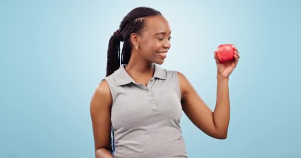 Twarz, hantle i czarna kobieta z ćwiczeniami, jabłko i wellness na niebieskim tle pracowni. Portret, osoba afrykańska i model z treningiem, fitness i sprzętem treningowym, owocami i zdrowiem. - Materiał filmowy, wideo