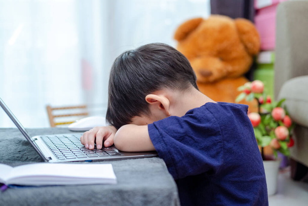 アジアの少年はラップトップでオンラインで勉強しながら眠る - 写真・画像