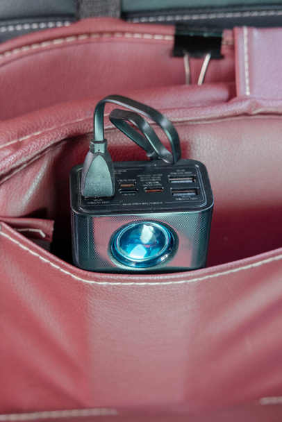 Banco de energía con cable de carga enchufado Almacene en el bolsillo del asiento trasero de su automóvil. - Foto, imagen