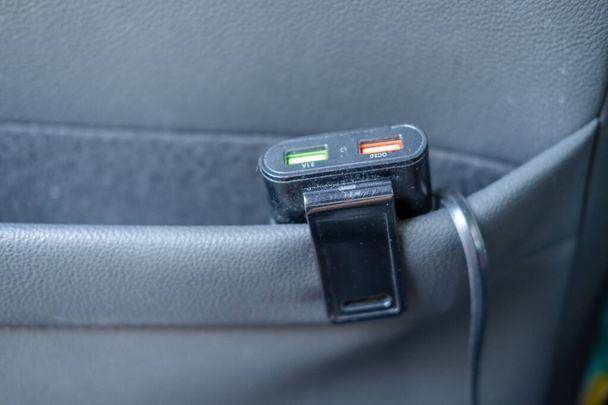 Banco de energía con cable de carga enchufado Almacene en el bolsillo del asiento trasero de su automóvil. - Foto, Imagen