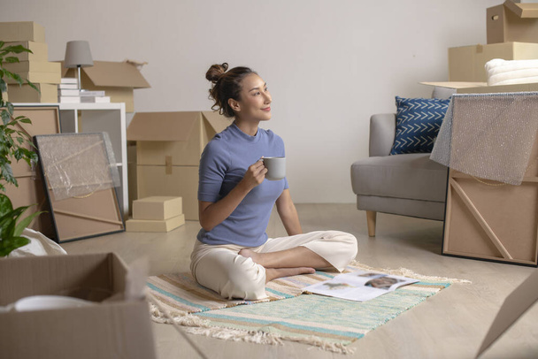 Happy young Asian woman sitting and resting in new house after moving in - Photo, Image