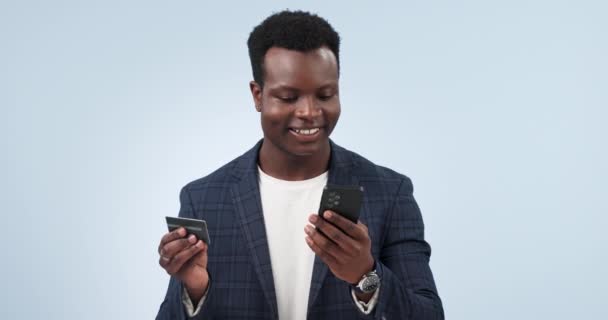 Hombre negro feliz, teléfono y tarjeta de crédito para el pago o compras en línea en un fondo de estudio. Hombre de negocios africano sonrisa con teléfono inteligente móvil para el comercio electrónico, aplicación bancaria o transacción en maqueta. - Metraje, vídeo