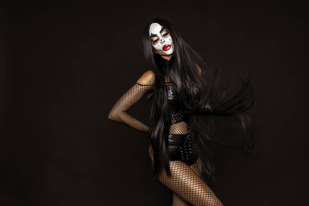Mulher sexy em uma maquiagem Halloween e traje no fundo preto. Maquiagem de Halloween e conceito de fantasia. - Foto, Imagem