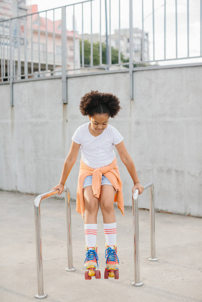 Αφροαμερικανό νεαρό κορίτσι με πατίνια που διασκεδάζει σε εξωτερικούς χώρους. - Φωτογραφία, εικόνα
