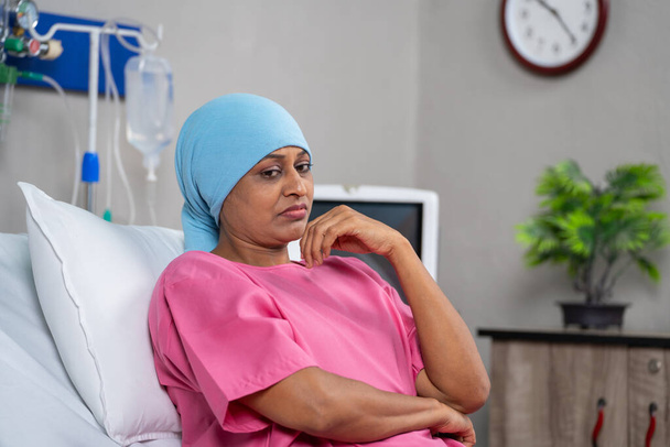 思慮深いインドの癌患者は,病院でベッドに座っている間深く考えています-孤独,治療,感情的な懸念の概念 - 写真・画像