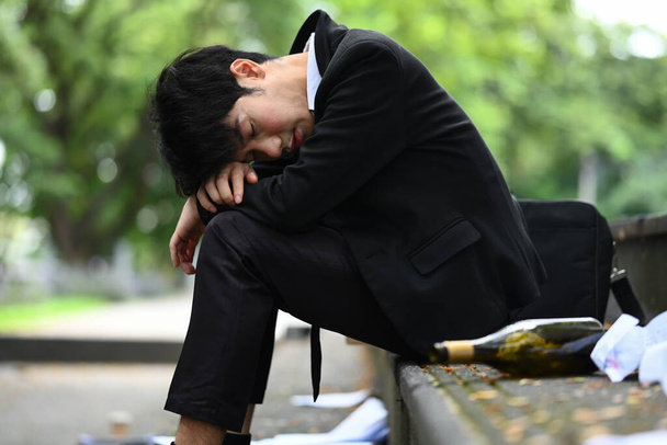 Пьяный бизнесмен, сидящий на лестнице на городской улице. Потерянные, безработные, проблемы с алкоголизмом или банкроты. - Фото, изображение
