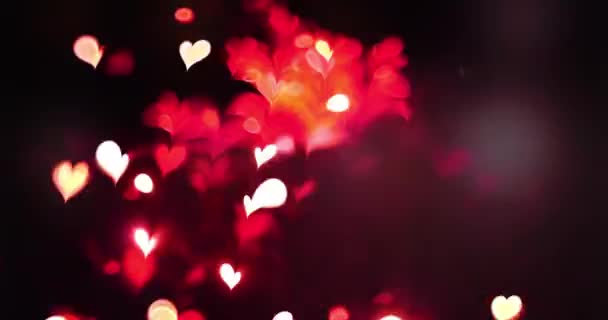 Red color love heart glowing with bokeh effect on black background. Romantic Abstract Motion Background. Valentine's Day, Festival Event, Wedding, Christmas, Diwali, Celebration, New Year. - Footage, Video
