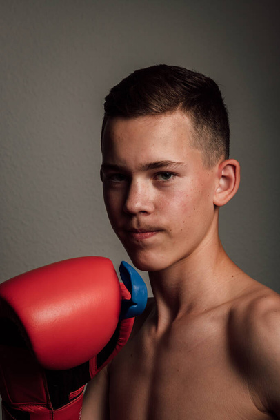 Teenage boxer sportovec trénuje boxovat na temném pozadí. Agresivní sport. Kvalitní fotografie - Fotografie, Obrázek
