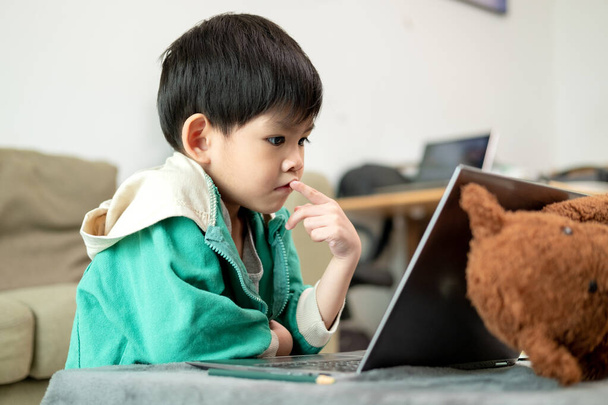 Asiático chico estudiando en línea y haciendo actividades en portátil - Foto, Imagen