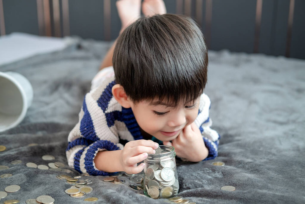 Asijský chlapec šťastně počítání mincí ušetřit peníze - Fotografie, Obrázek
