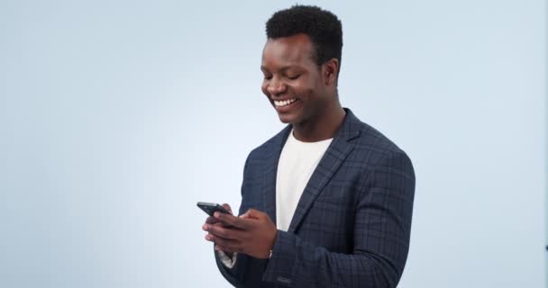 Hombre negro feliz, teléfono y mecanografía para las redes sociales o la comunicación en un fondo de estudio. Hombre de negocios africano sonrisa en el chat en línea, mensajes de texto o redes en la aplicación de teléfonos inteligentes móviles en la maqueta. - Imágenes, Vídeo