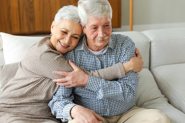 Yetişkin bir çiftin evde kucaklaşması. Orta yaşlı karı ve koca şefkatle kucaklaşıp tatlı bir bağ kurmanın tadını çıkarıyorlar. Büyükannem ve büyükbabam birlikte. Aile zamanı sevgi ve ilgi - Fotoğraf, Görsel