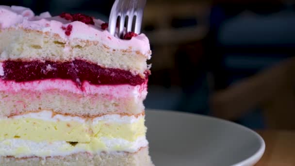 Κοντινό πλάνο ενός ροζ κέικ φράουλα στροβιλίζεται σε ένα λευκό πιάτο. Τρώγοντας τσιζκέικ με πιρούνι. Δαγκώνω τσιζκέικ. Γλυκό επιδόρπιο - Πλάνα, βίντεο