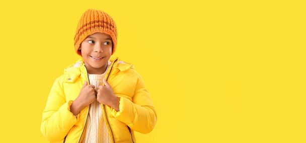 Cute African-American boy in warm winter clothes on yellow background with space for text - Foto, immagini