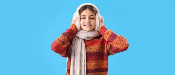 Petite fille mignonne en vêtements d'hiver sur fond bleu - Photo, image