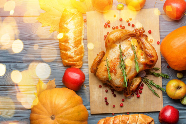 Sabroso pavo al horno y diferentes alimentos para el día de Acción de Gracias sobre fondo de madera gris - Foto, imagen