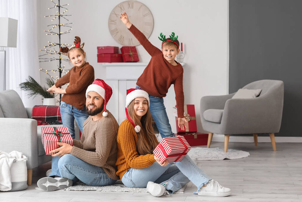 Pais felizes e seus filhos pequenos com presentes de Natal em casa - Foto, Imagem