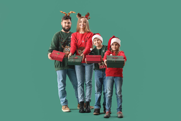 Happy family with Christmas gifts on green background - Photo, Image