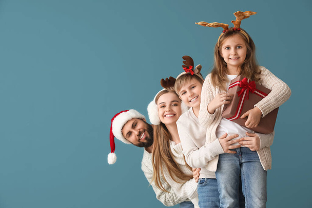 Glückliche Familie mit Weihnachtsgeschenk auf blauem Hintergrund - Foto, Bild