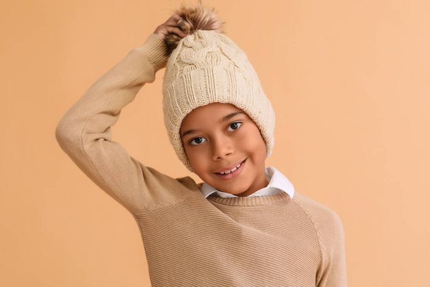 ベージュの背景に暖かい冬の服でかわいいアフリカ系アメリカ人の少年 - 写真・画像
