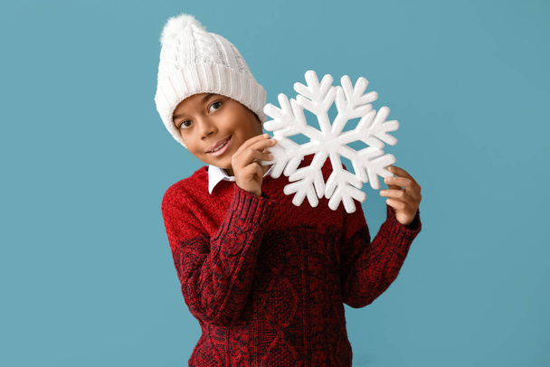 Симпатичный афроамериканец в теплой зимней одежде и со снежинкой на синем фоне - Фото, изображение