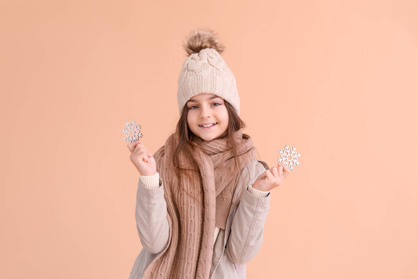 Cute little girl in winter clothes with snowflakes on beige background - Photo, Image