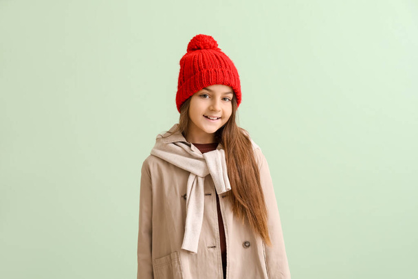 Cute little girl in winter clothes on green background - Photo, Image