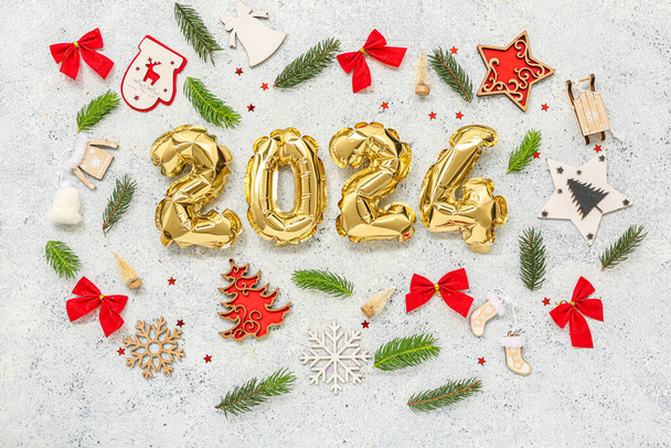 Composizione con figura 2024 fatta di palloncini di stagnola, diverse decorazioni natalizie e rami di abete su sfondo chiaro - Foto, immagini