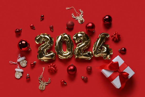 Figura 2024 hecha de globos de aluminio con decoraciones navideñas sobre fondo rojo - Foto, Imagen