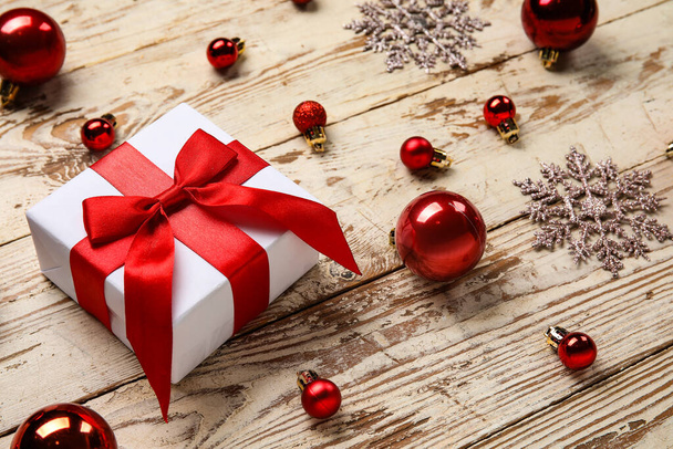 Різдвяні кульки з подарунковою коробкою та сніжинками на білому дерев'яному фоні - Фото, зображення