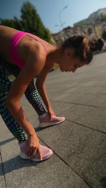 Eine elegante Sportlerin in farbenfroher Sportkleidung absolviert auf den Straßen der Stadt ein Aufwärmprogramm. Hochwertiges 4k Filmmaterial - Filmmaterial, Video