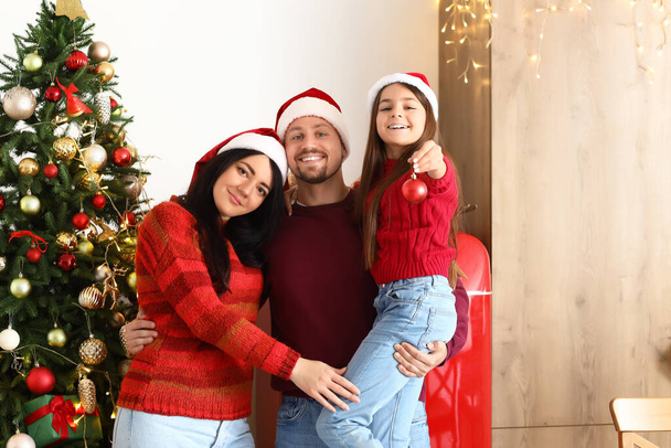 Niña con bola de Navidad y sus padres en casa - Foto, Imagen